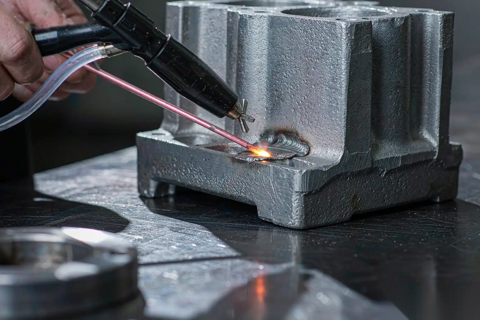 Technician repairing a cast aluminum part with a welding torch