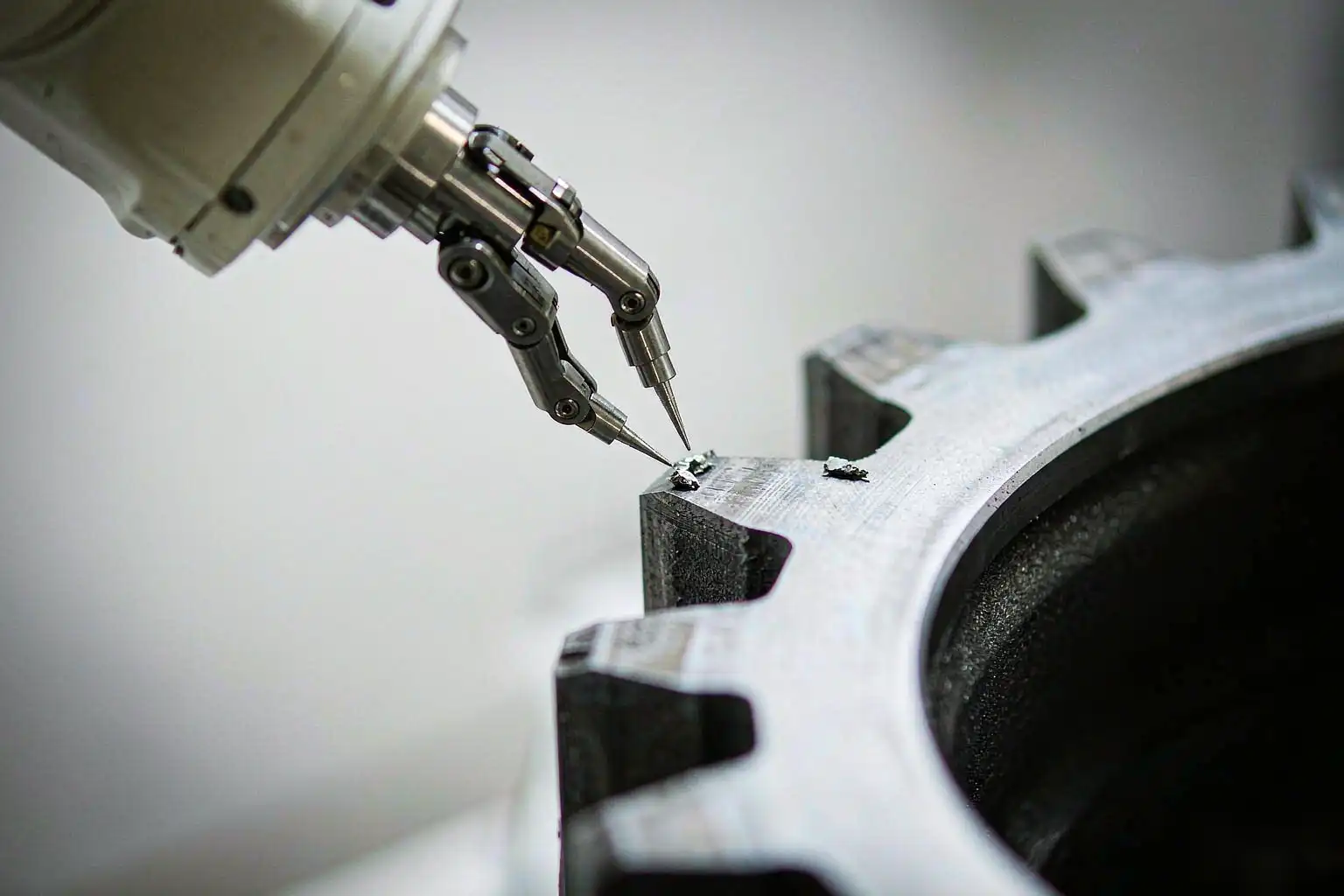 Robotic deburring cell clearing burrs from a metal gear tooth flank and root