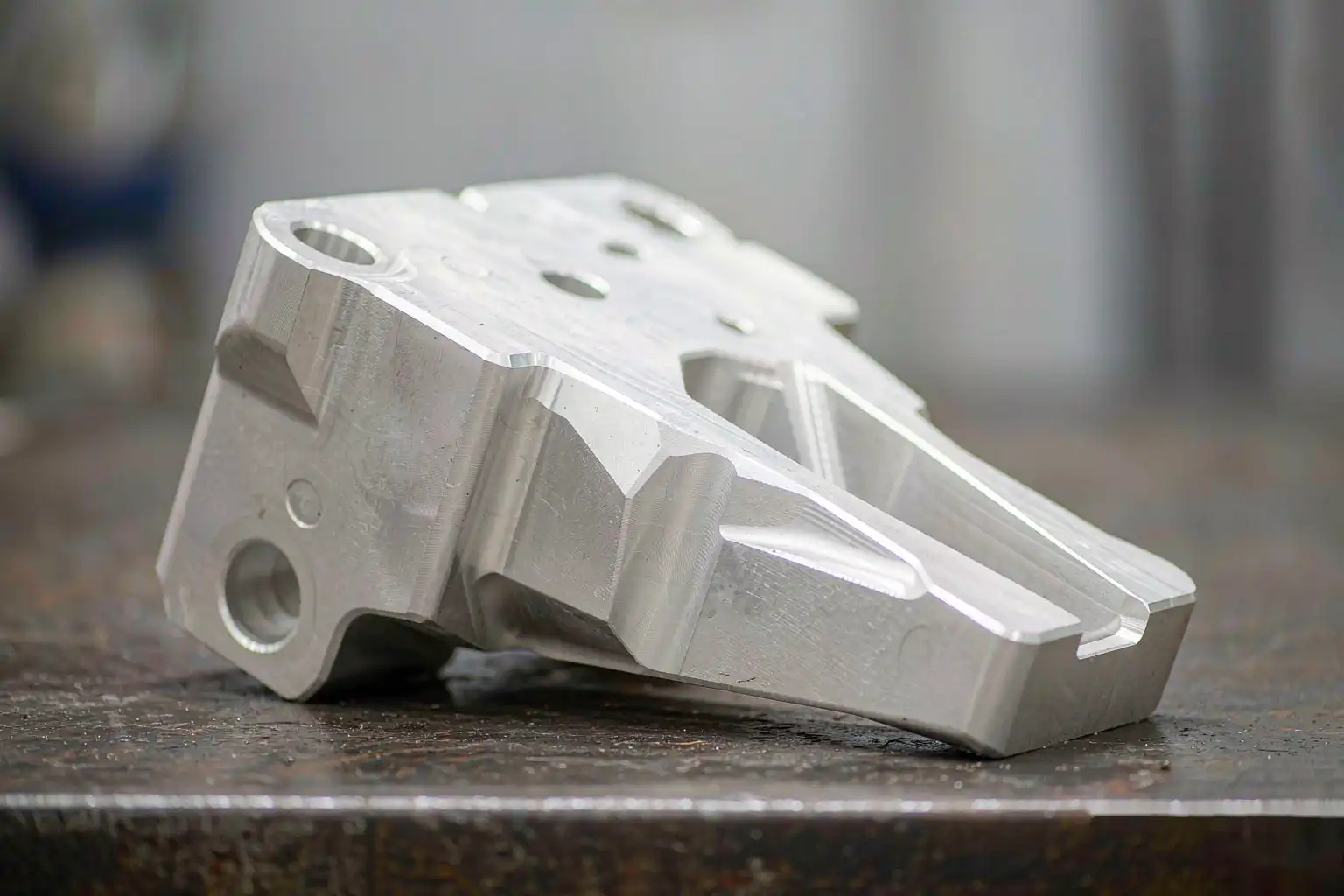 As-cast aluminum automotive bracket component on a workbench before machining