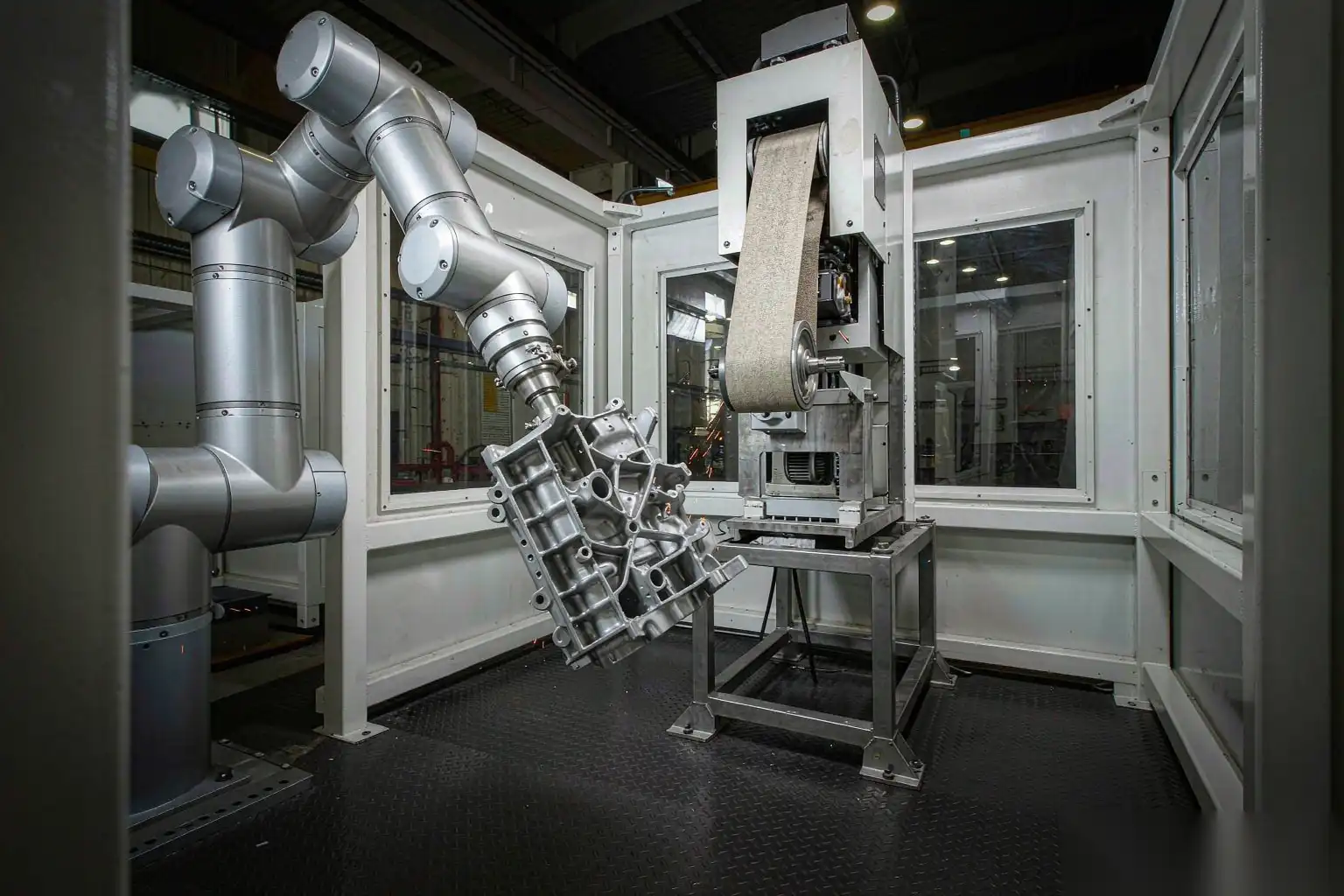 Robot holding a die cast part against a mounted grinding belt