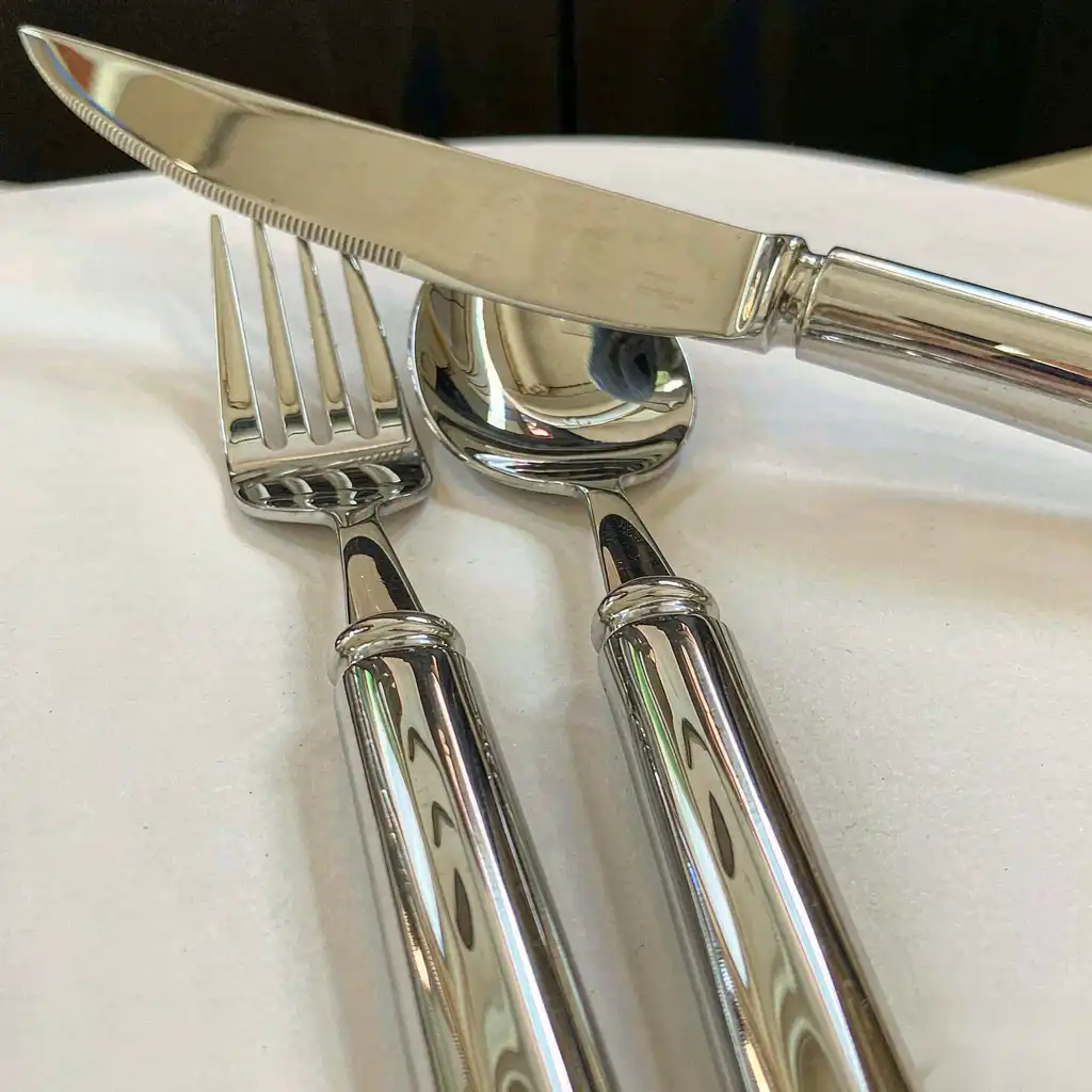 Finished stainless cutlery showing a bright uniform polish on blades and handles